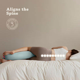 Person lying on a bed with a bbhugme pregnancy pillow 